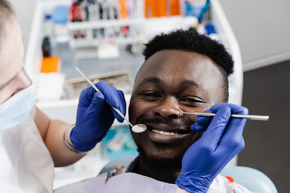 Happy african american patient of dentistry. Teeth treatment. Handsome african man sitting in dental office and smiling. Dentist visiting and consultation