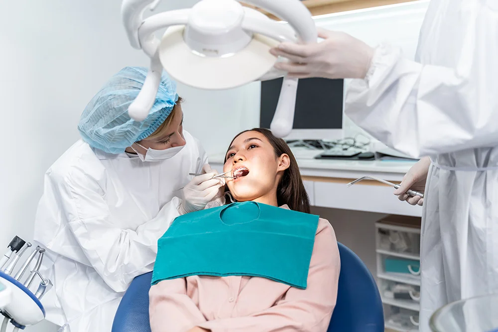 Orthodontist doctor examine tooth to women patient at dental clinic. Attractive young girl with braces lying on dental chair, getting dental treatment from dentist during procedure service in hospital