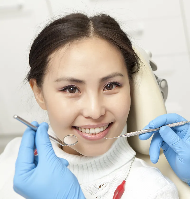 People, medicine, stomatology and health care concept - male dentist with mirror checking patient woman up at dental clinic office